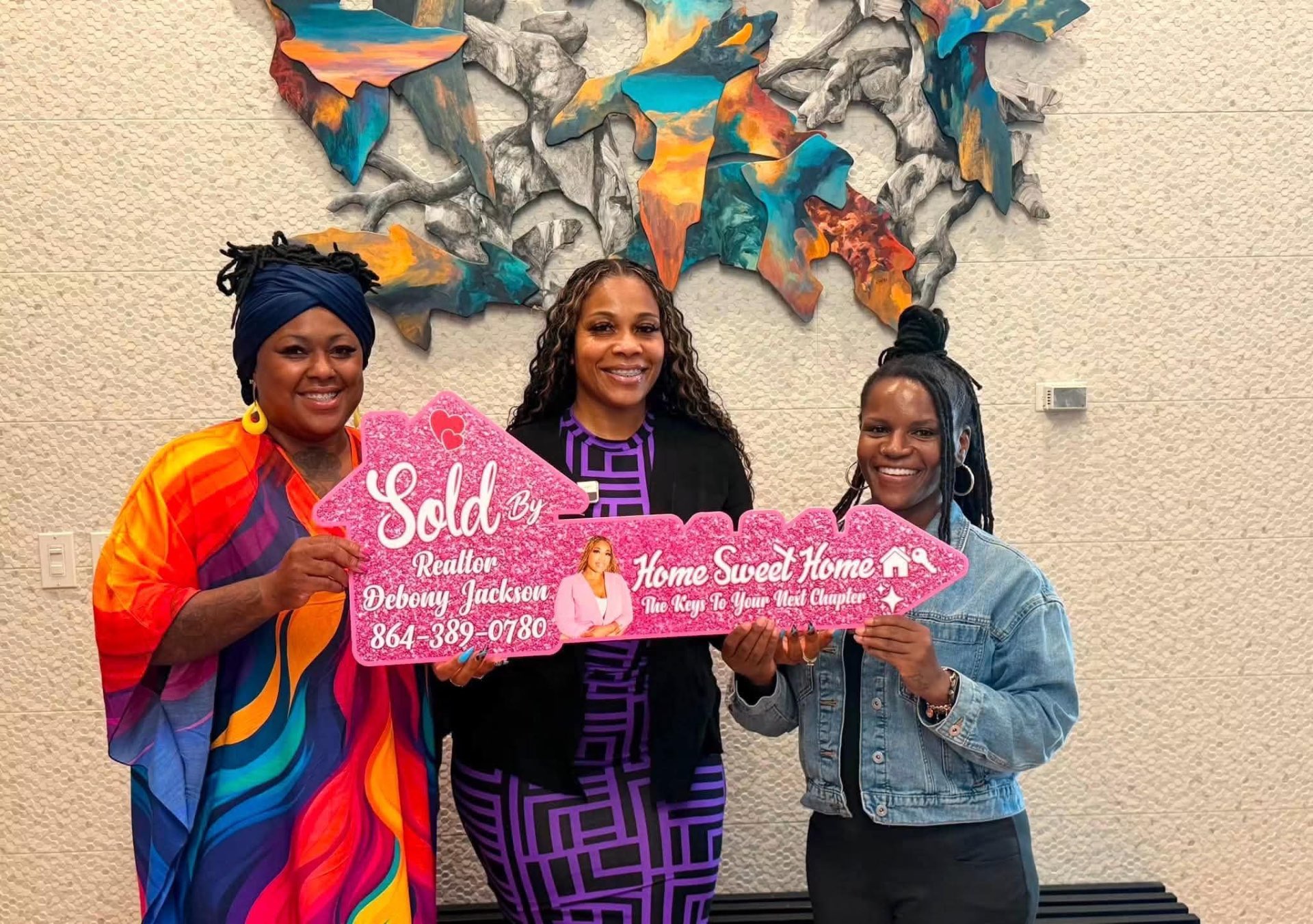 Debony Jackson with happy clients holding a pink Sold By Realtor Debony Jackson key sign